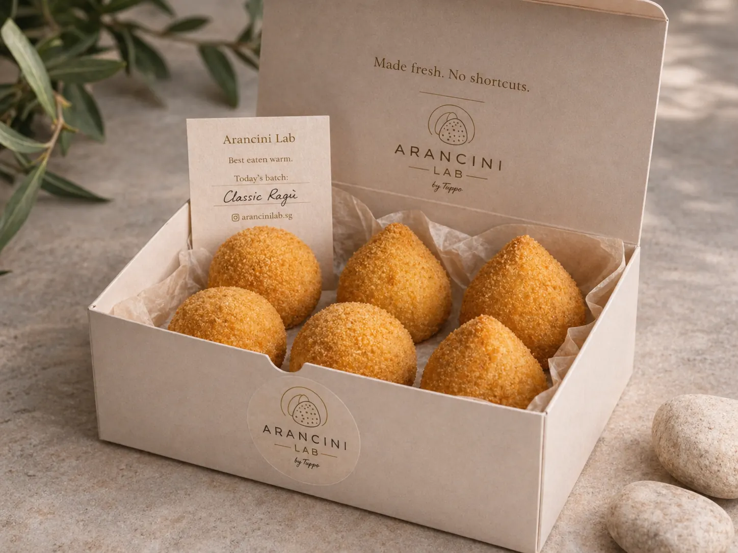 Three Sicilian arancini by Tuppo & Co on a dark stone surface
