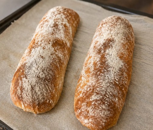 Two slow-fermented ciabatta loaves on baking paper